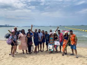 A lively group of friends poses for a photo on the beach, capturing the joy of their day by the water — perfect for memorable outings and celebrations.