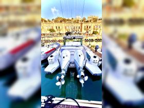 A striking view of the back of a motorboat named 'ADELE II' docked in a marina, showcasing its powerful twin engines and fishing gear, perfect for a day out on the water.