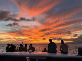 A group of friends enjoys a stunning sunset aboard a boat, creating a perfect backdrop for memorable moments and celebrations on the water.