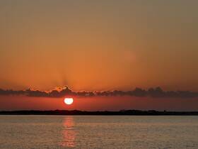 A stunning sunset over calm waters, creating a picturesque backdrop for evening boat cruises or romantic getaways.