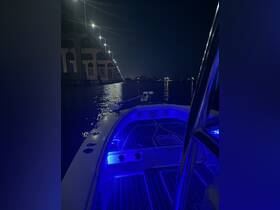 A serene view of the boat's interior illuminated by blue lights at night, showcasing the helm and deck area — perfect for nighttime cruising.