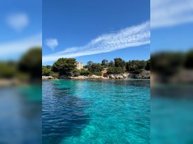 A stunning view of a serene coastline with crystal-clear waters and lush greenery, perfect for exploring hidden gems by boat.
