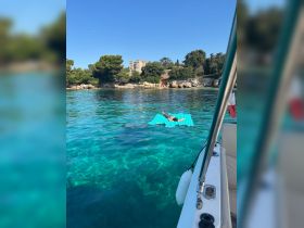 A child enjoys a relaxing moment on a floating mat in the crystal-clear waters, surrounded by stunning coastal scenery — a perfect summer getaway.