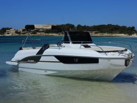 A sleek speedboat named 'Flyer' anchored in shallow waters, showcasing its modern design against a picturesque coastal backdrop.