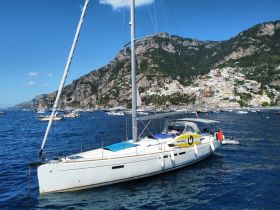 A picturesque sailboat anchored in clear blue waters, with the stunning coastal town of Positano in the background, perfect for exploring the Amalfi Coast.