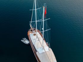 Aerial view of a stunning yacht anchored in calm waters, showcasing its elegant design and spacious deck — perfect for luxury sailing experiences.