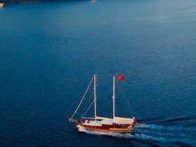 An aerial view of a beautiful sailboat cruising through calm blue waters, showcasing the vessel's elegant design and the serene maritime environment.