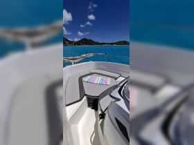 A cozy seating area on a boat, featuring a colorful towel laid out on the lounge, perfect for relaxing under the sun while enjoying the beautiful turquoise waters.