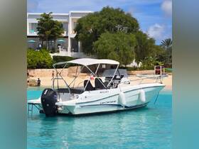 A sleek Cap Camarat boat docked in clear turquoise waters, with a picturesque beach and tropical scenery in the background, perfect for a day of relaxation on the water.