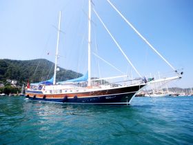 A stunning side view of a yacht docked in clear waters, surrounded by lush green hills — perfect for luxury charters and scenic cruises.