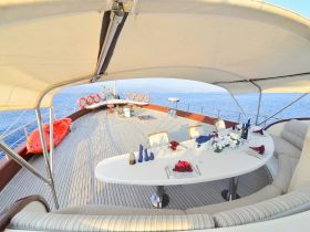 An elegant dining area on a yacht, featuring a beautifully set table and comfortable seating, perfect for enjoying meals while cruising on the open water.