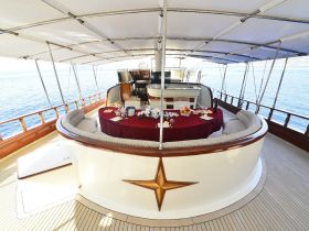 An elegant interior view of a yacht's dining area, featuring a plush seating arrangement and a beautifully set table, perfect for luxurious onboard dining experiences.