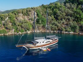 A stunning aerial view of a beautifully crafted yacht anchored in serene waters, surrounded by lush greenery — perfect for luxury sailing experiences.