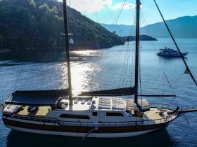 A stunning aerial view of a luxurious yacht docked in serene waters, surrounded by lush hills — perfect for exploring beautiful coastlines.