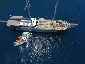 A stunning aerial view of a luxurious yacht anchored in deep blue waters, showcasing various water sports equipment ready for adventure.