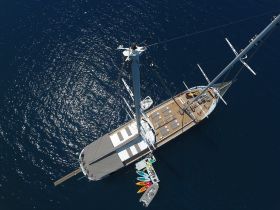 A stunning aerial view of a luxurious yacht cruising through deep blue waters, showcasing its elegant design and spacious deck.