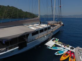 A stunning aerial view of a luxurious yacht docked in clear waters, showcasing paddleboards and kayaks ready for adventure.