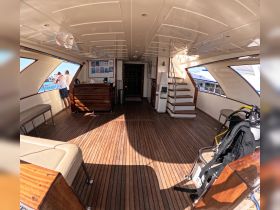 Interior view of a spacious boat cabin featuring seating and a helm area, with guests enjoying the view through the windows — perfect for relaxing and planning adventures on the water.