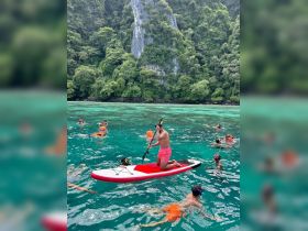 A vibrant scene of snorkelers enjoying the crystal-clear waters while a paddleboarder navigates nearby — a perfect tropical adventure for water enthusiasts.