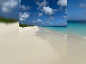 A stunning view of a pristine beach with soft white sand and turquoise waters, perfect for a relaxing getaway or beach day.