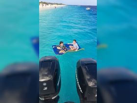 Two children enjoy a sunny day floating on a mat in crystal-clear waters, capturing the essence of fun beach activities.