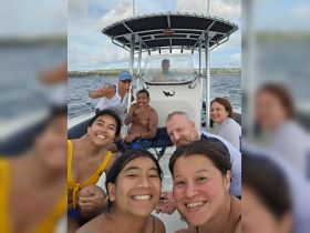 A joyful group of friends and family poses for a selfie on a boat, capturing the essence of fun and adventure on the water.