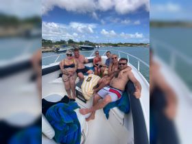 A cheerful group enjoys a fun day on the boat, showcasing camaraderie and celebration under the sunny sky.