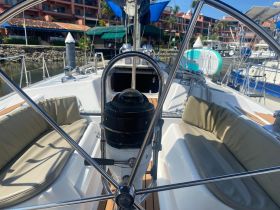 A well-appointed helm area of a sailboat featuring comfortable seating and a clear view of the marina, perfect for relaxing before setting sail.