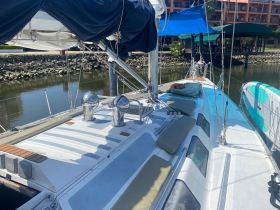 A view of the interior deck of a sailboat, showcasing comfortable seating and helm area, perfect for relaxing while cruising.