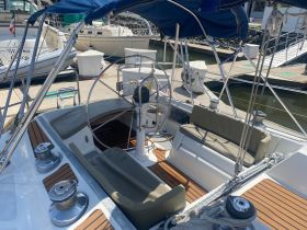 A well-appointed helm area of a sailboat featuring comfortable seating and a polished wooden deck, perfect for navigating the open waters.