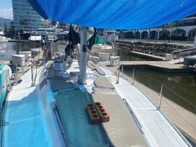 A spacious view of the interior seating area on a sailboat, featuring comfortable cushions and a serene marina backdrop, perfect for relaxing before setting sail.