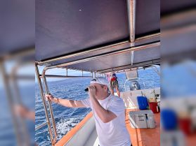 A guest on a boat uses binoculars to explore the horizon, capturing the essence of adventure on the water.