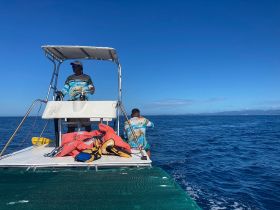 Two crew members navigate a boat on open waters, showcasing the adventure and excitement of a day at sea.