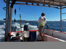 A fisherman enjoys a day out on the ocean, casting lines from a boat while showcasing the thrill of fishing in beautiful waters.