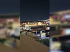 A sleek yacht docked at night, illuminated by surrounding lights, showcasing a serene marina atmosphere.