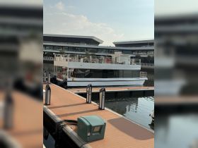 A spacious boat docked at a modern marina, showcasing its sleek design against a backdrop of contemporary architecture.