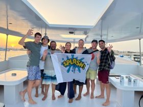 A lively group of friends celebrates on the deck of a boat at sunset, showcasing a fun and memorable boating experience.