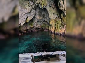 A stunning view of a cave with crystal-clear waters, captured from the deck of a boat — an ideal spot for exploration and adventure.