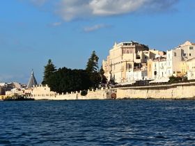 A picturesque view of a coastal city with historic architecture along the waterfront, showcasing the beauty of the harbor and surrounding landscape.