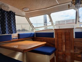 Interior view of a boat cabin featuring comfortable seating and a dining area, perfect for relaxing while on the water.