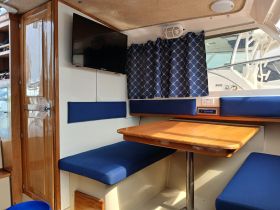 Interior view of a cozy boat cabin featuring comfortable seating and a dining table, perfect for relaxing during a day on the water.
