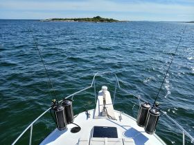 A view from the front of a fishing boat, showcasing the calm waters and distant shoreline, perfect for a day of fishing adventures.