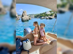 Two children enjoy the view from a boat, overlooking stunning rocky formations and a picturesque coastline — a perfect moment of adventure on the water.