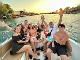 A lively group enjoys a sunset boat party, capturing joyful moments with friends and family on the water.