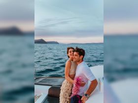 A joyful couple embraces on the deck of a yacht, celebrating against a stunning sunset backdrop — perfect for romantic getaways or special occasions on the water.
