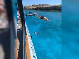 A thrilling moment captured as a person dives into the crystal-clear waters from a boat, showcasing the excitement of summer adventures on the water.