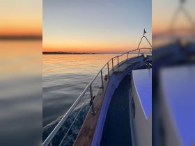 A serene view of a boat at sunset, showcasing the tranquil waters and the vessel's sleek profile — perfect for evening cruises.