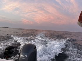 A serene view of the ocean at sunset, showcasing the boat's wake and a beautiful sky, perfect for capturing the essence of a peaceful boating experience.
