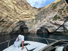 A guest enjoys the stunning view of a rocky cave while aboard a boat, showcasing the beauty of coastal exploration.