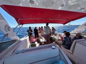 A lively group enjoys a day on the water aboard a luxurious boat, complete with drinks and snacks, perfect for celebrations and social gatherings.